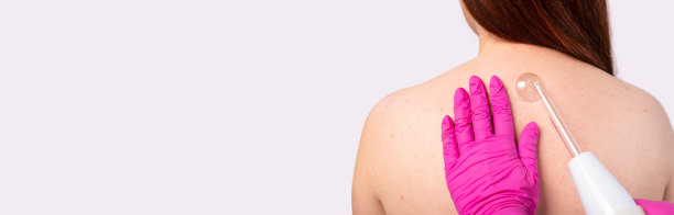 横幅,长格式。放大的女人的背部照片。美容师的手和达森瓦尔。皮肤清洁和按摩。灰色背景和充足的侧空间的广告图片下载