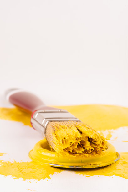 油漆刷躺在打开的黄色油漆罐的盖子上图片下载