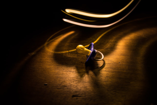 木制桌子上的婴儿奶嘴，背景低调。图片下载