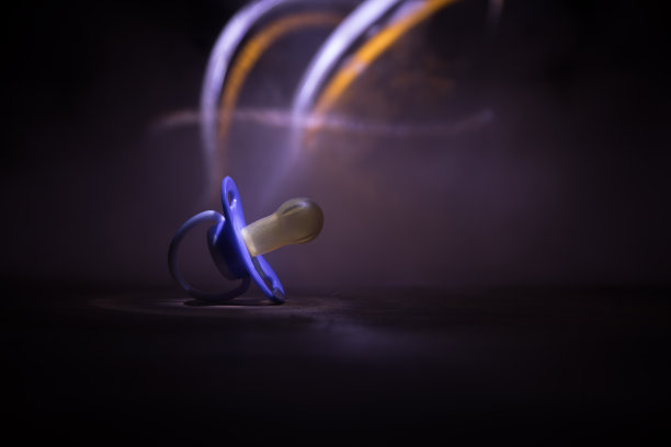 木制桌子上的婴儿奶嘴，背景低调。图片下载