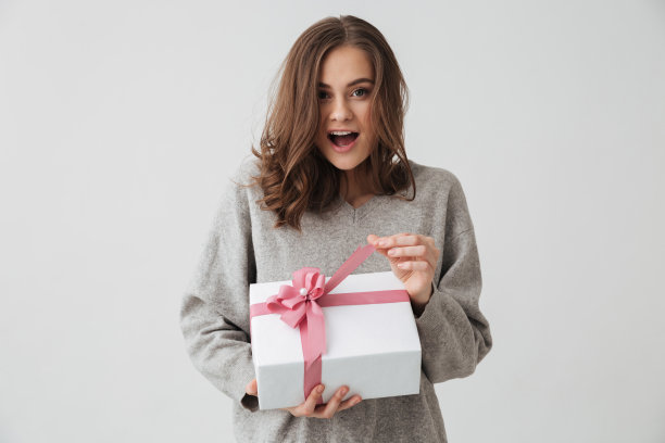 惊喜快乐的褐发女人在毛衣持有礼盒图片下载