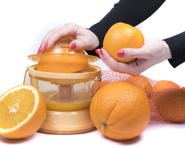 电动榨汁机与切橙分离在白色背景上。Womenâ的手工制作新鲜橙汁。图片下载