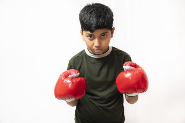 白色背景下戴着拳击手套的小男孩。图片下载
