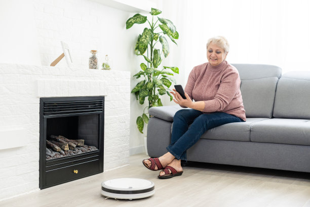 人、休闲、家居和科技概念——老年妇女、机器人在家真空清洁地板图片下载