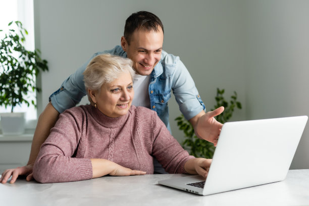 成年的母亲和儿子坐在桌子旁，在笔记本电脑上考虑新软件图片下载
