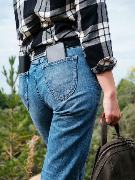 移动电源和智能手机在女孩牛仔裤后面的口袋里，特写镜头。在生活中使用现代科技的概念。现代女孩总是保持联系。方便的小工具,徒步旅行图片下载