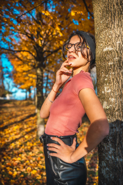 一名身穿粉色衬衫、黑色裙子、戴着眼镜的黑发女子在秋季拍摄图片下载
