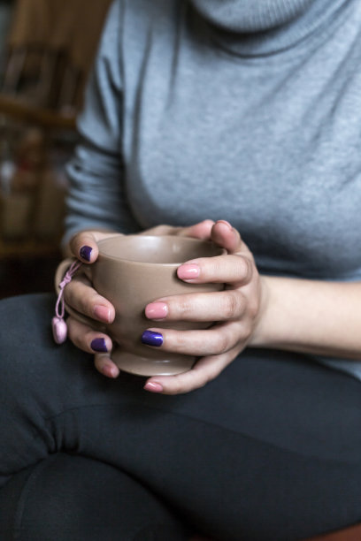 一个年轻女子的手拿着一杯咖啡，特写图片下载