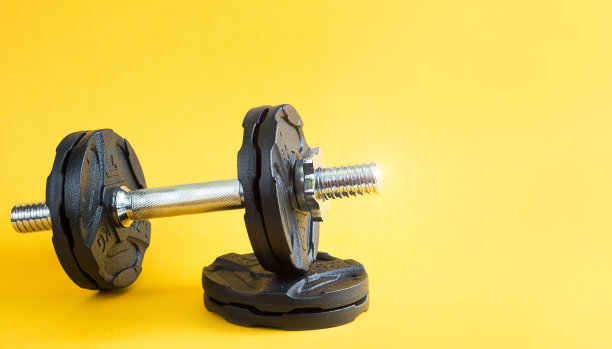 带有黄色背景的哑铃。运动生活方式，力量训练，健身房。复制空间图片下载