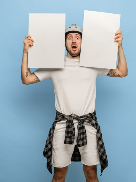 年轻的震惊的男子与空白纸孤立在蓝色的背景图片下载