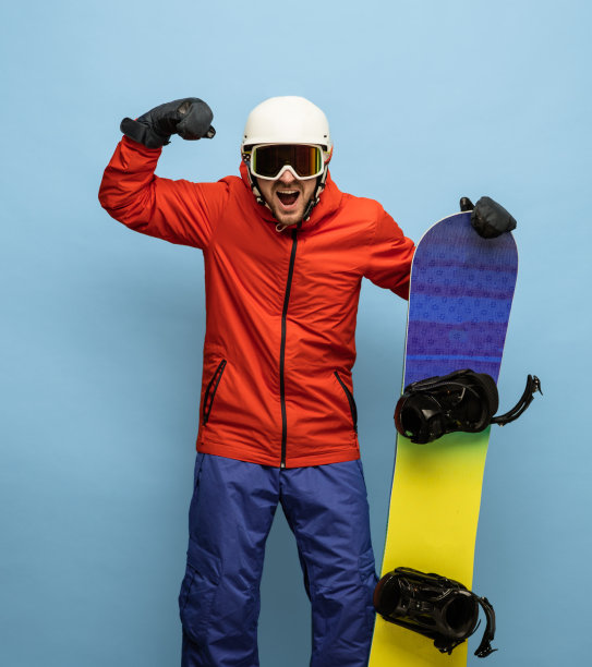 男性滑雪板在明亮的滑雪服与滑雪板孤立在蓝色背景。图片下载