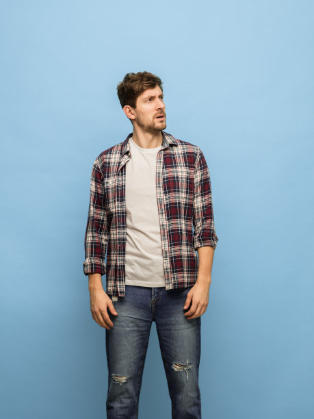 严肃的年轻人在休闲服装摆出孤立的蓝色背景。图片下载