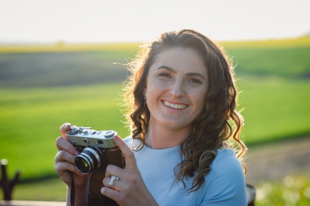 近距离的微笑美丽的女孩拍照在复古相机。一个穿着蓝色裙子的女孩面带微笑，手里拿着一台复古相机。小屋里拿着相机的女孩图片下载