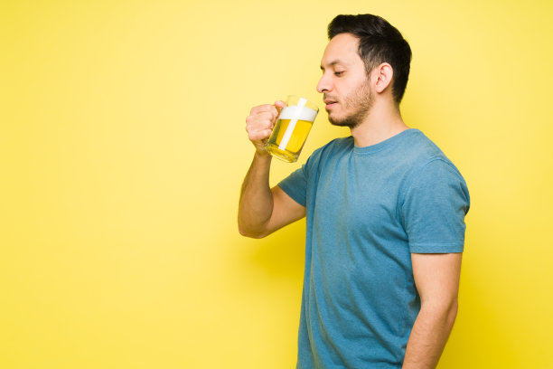 口渴的年轻人在明亮的背景下喝着冰啤酒图片下载