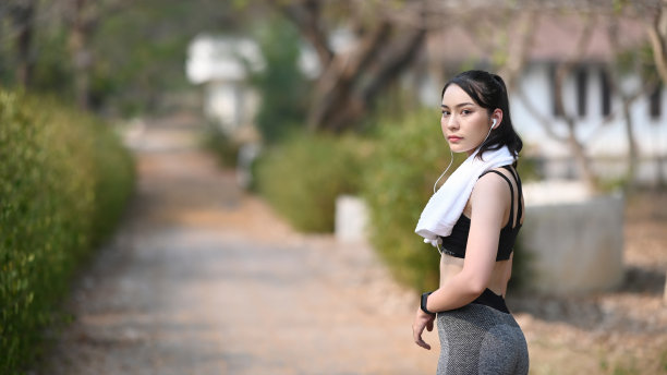 健身妇女在运动服装与白色毛巾户外运动。图片下载