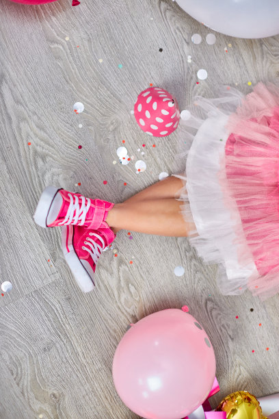 创意摆出了时髦的女孩的腿在粉红色的运动鞋和裙子，平躺图片下载