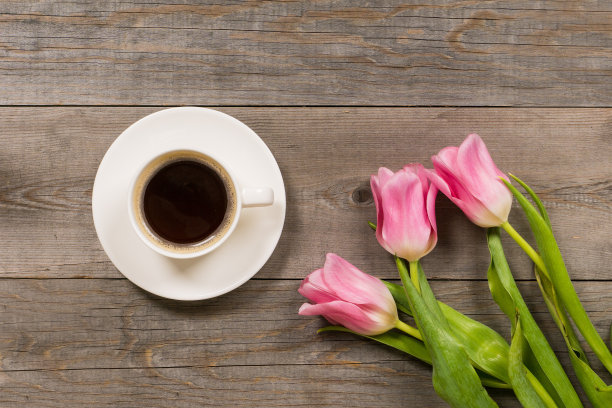 新鲜的粉红色郁金香放在灰色的木质老桌面上，早上好或问候花束与白色的咖啡杯图片下载