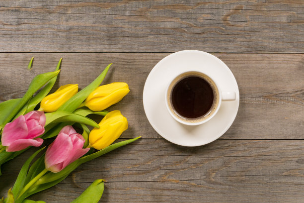 新鲜的粉红色郁金香放在灰色的木质老桌面上，早上好或问候花束与白色的咖啡杯图片下载