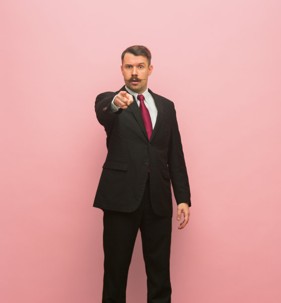 年轻商人的肖像孤立地站在粉红色的背景。图片下载