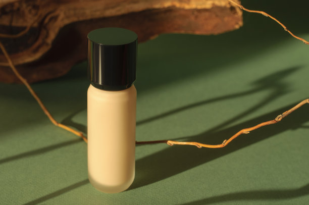 保湿粉底，瓶装。化妆品遮瑕膏。粉底:抽象的绿色背景，木制的树枝和阴影图片下载