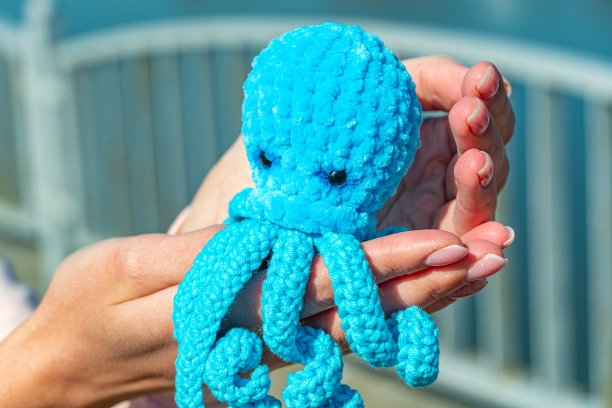 蓝色的针织章鱼在女性的手特写，针织玩具在章鱼的形式图片下载