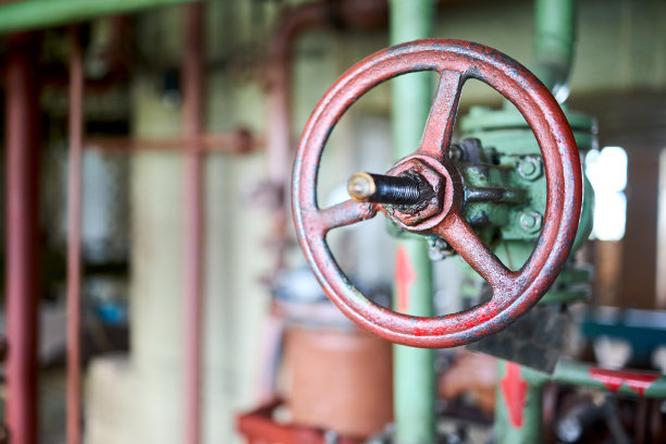 工业化学复古风格绿色阀门石化特写与选择性的焦点在棕色方向盘上安装与法兰连接的绿色管道上脱离焦点前景与copyspace。图片下载