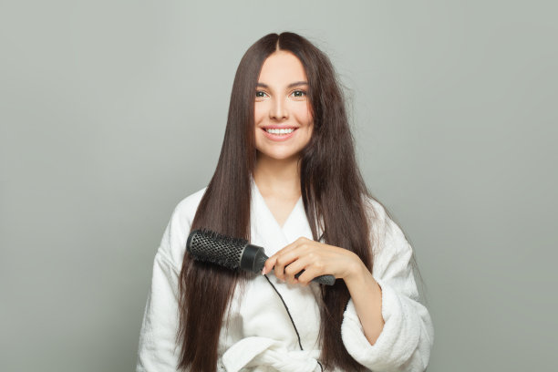 美丽的女人在白底上梳理着她棕色的长发。护发概念图片下载