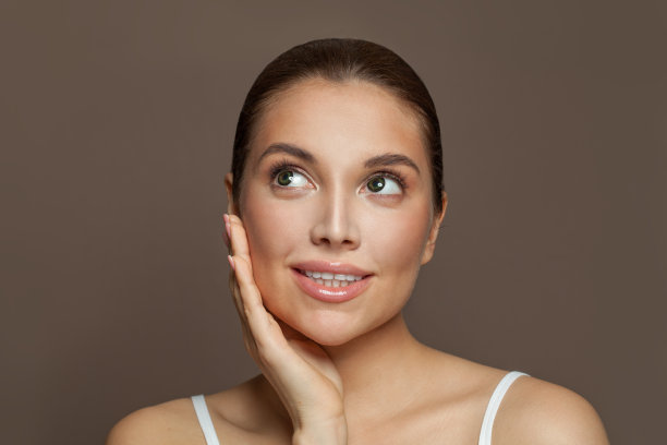 开朗的年轻女子，皮肤清澈，微笑着，向上看。护肤和面部护理的概念图片下载