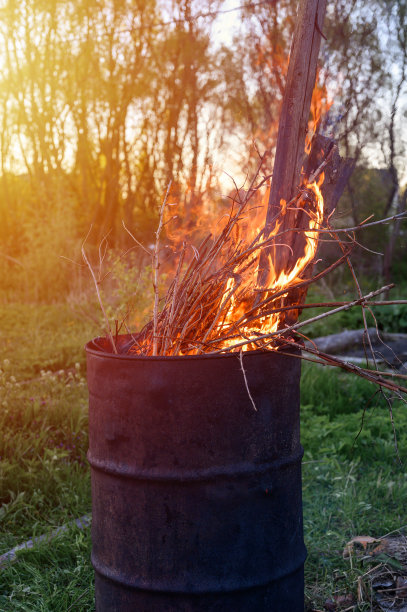 在生锈的铁桶里焚烧垃圾。燃烧着地上的树枝和老草。后院和花园的春季大扫除。这是春季烧草的安全替代品。耀斑图片下载