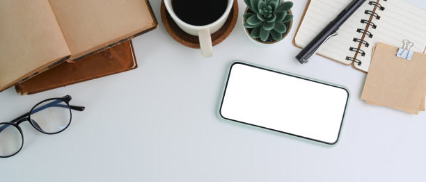白色办公桌的水平照片，智能手机，眼镜，咖啡杯，笔记本和多肉植物。图片下载