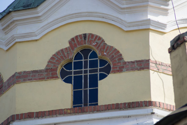 一座教堂的墙是黄色和橙色的石头，窗户形成了十字形，宗教建筑，建筑细节，特写图片下载