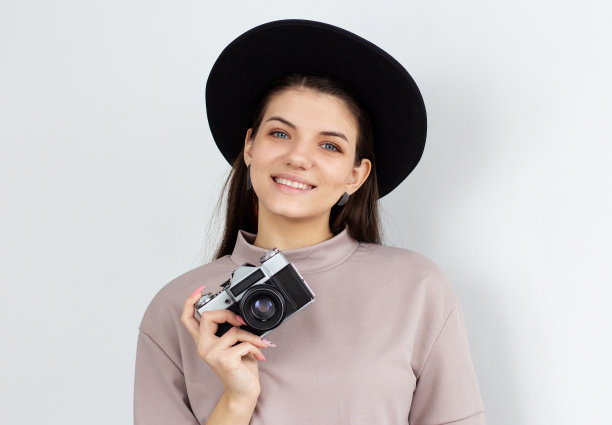 工作室拍摄的快乐女孩拿着相机。欧洲女模特在白色背景上拍照。图片下载