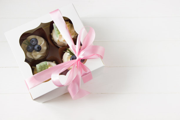 奶油芝士和新鲜蓝莓纸杯蛋糕，白色纸盒，粉色蝴蝶结，白色背景。浆果纸杯蛋糕在快递盒里。甜食交付图片下载