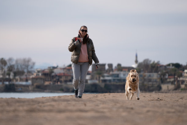 快乐的女人和她可爱的金毛猎犬一起奔跑和玩耍图片下载