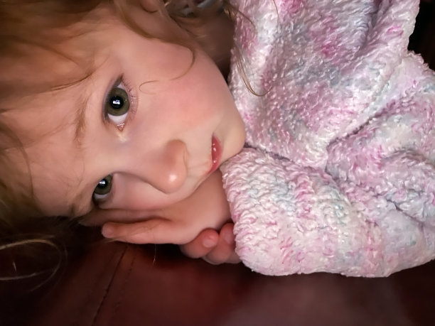 蹒跚学步的小女孩穿着浴袍看着数字平板电脑图片下载