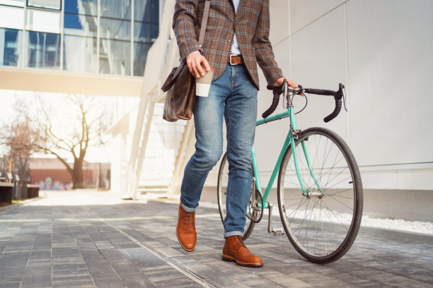 一个不知名的时尚男子骑着自行车走在城市的街道上图片下载