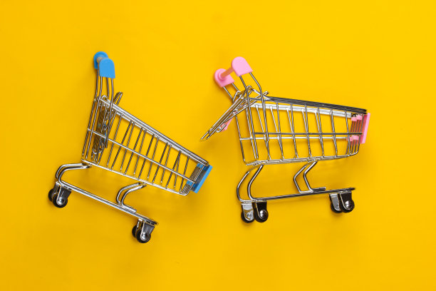 两辆黄色背景的迷你超市手推车。购物的概念。俯视图图片下载