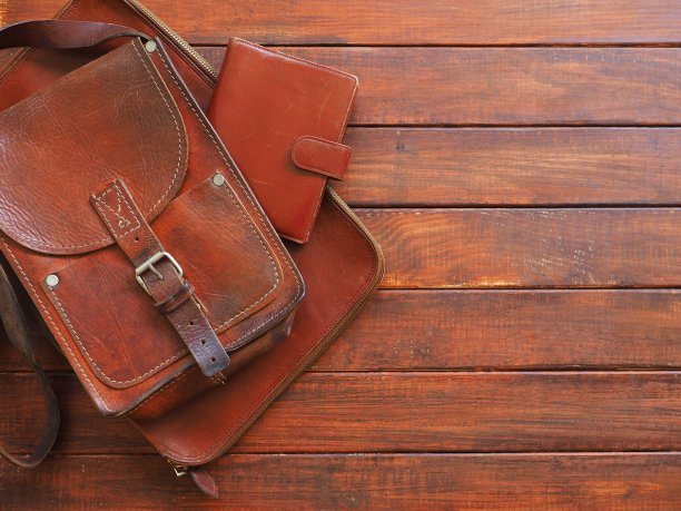 皮革手袋与笔记垫在旧的木制背景图片下载