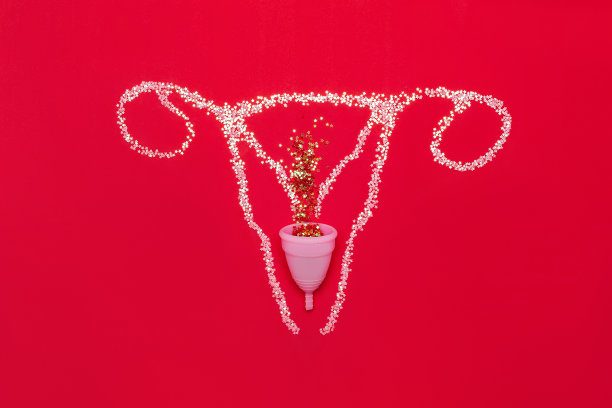 红色背景上有闪光的雌性生殖器官的布局。平放月经杯。图片下载