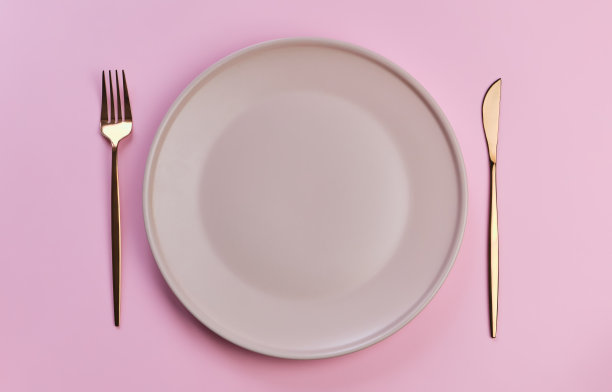 粉红色背景上的粉红色盘子和餐具。完美的浪漫晚餐图片下载
