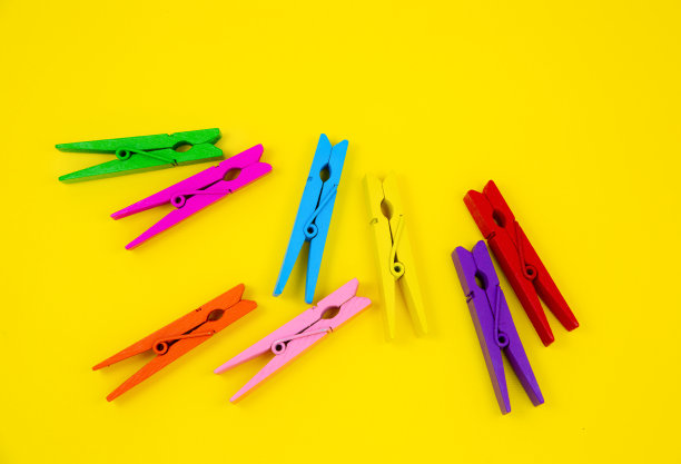 黄色背景上的彩色木衣夹。关闭，复制空间。极简主义，原创和创意的照片。是另一个。个性的概念。图片下载