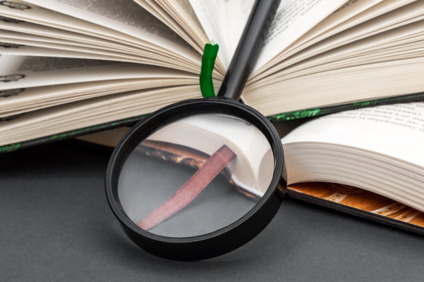 放大镜与打开的书在黑色。关闭了。图片下载