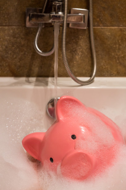 在装满水的浴缸里存钱罐，节约洁净水的概念，垂直拍照图片下载