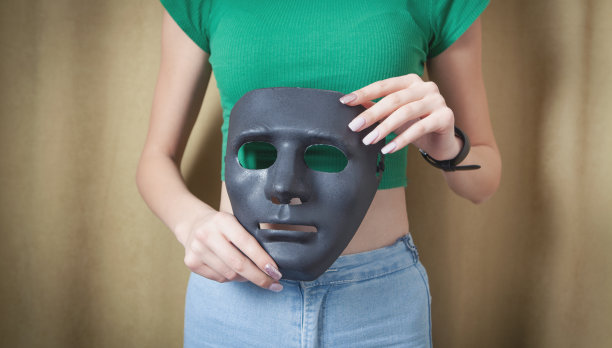 拿着黑色面具的年轻女子。假的,匿名图片下载