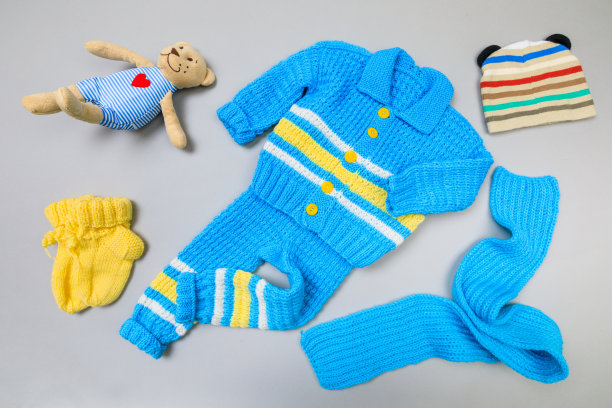 婴儿的概念。灰色背景的手工编织婴儿套装。文本。从以上观点。平躺图片下载