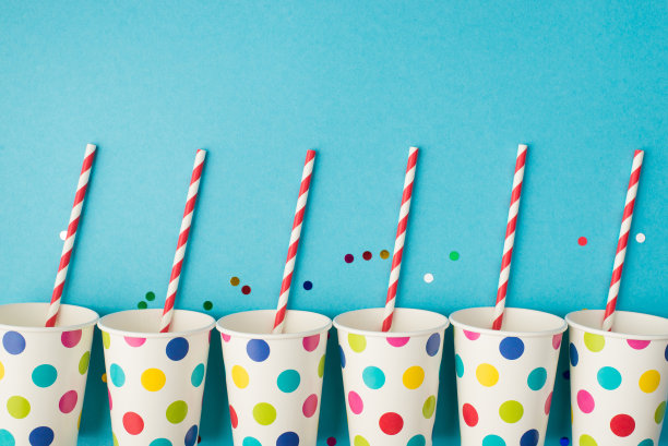 顶视图照片的生日聚会组成亮片和波尔卡圆点纸杯条纹吸管在孤立的蓝色背景与copyspace图片下载