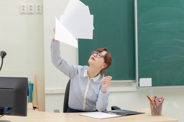 可爱的女老师在她的工作地点坐在桌子上，手里拿着文件完成任务后图片下载