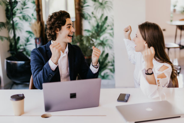 我们赢了。在商务会议中，坐在办公室桌子旁的愉快的年轻人看起来很兴奋图片下载