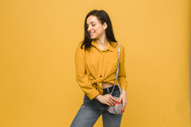 概念照片的年轻女性与钱包，微笑，看起来很高兴。身穿黄色衬衫，孤立黄色背景图片下载