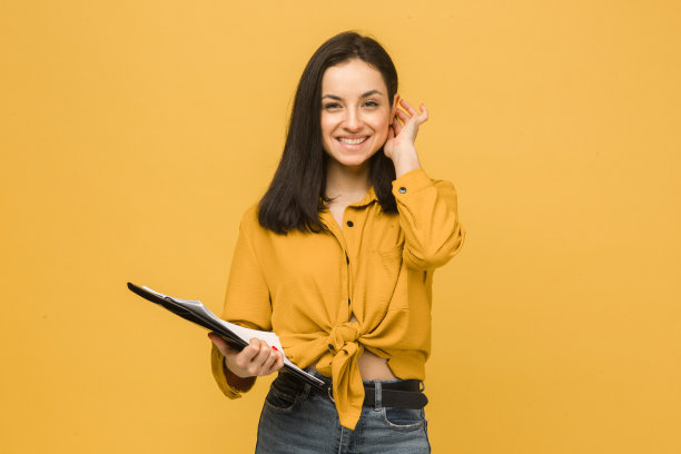 商务女士手持文件的概念照片。身穿黄色衬衫，孤立黄色背景图片下载